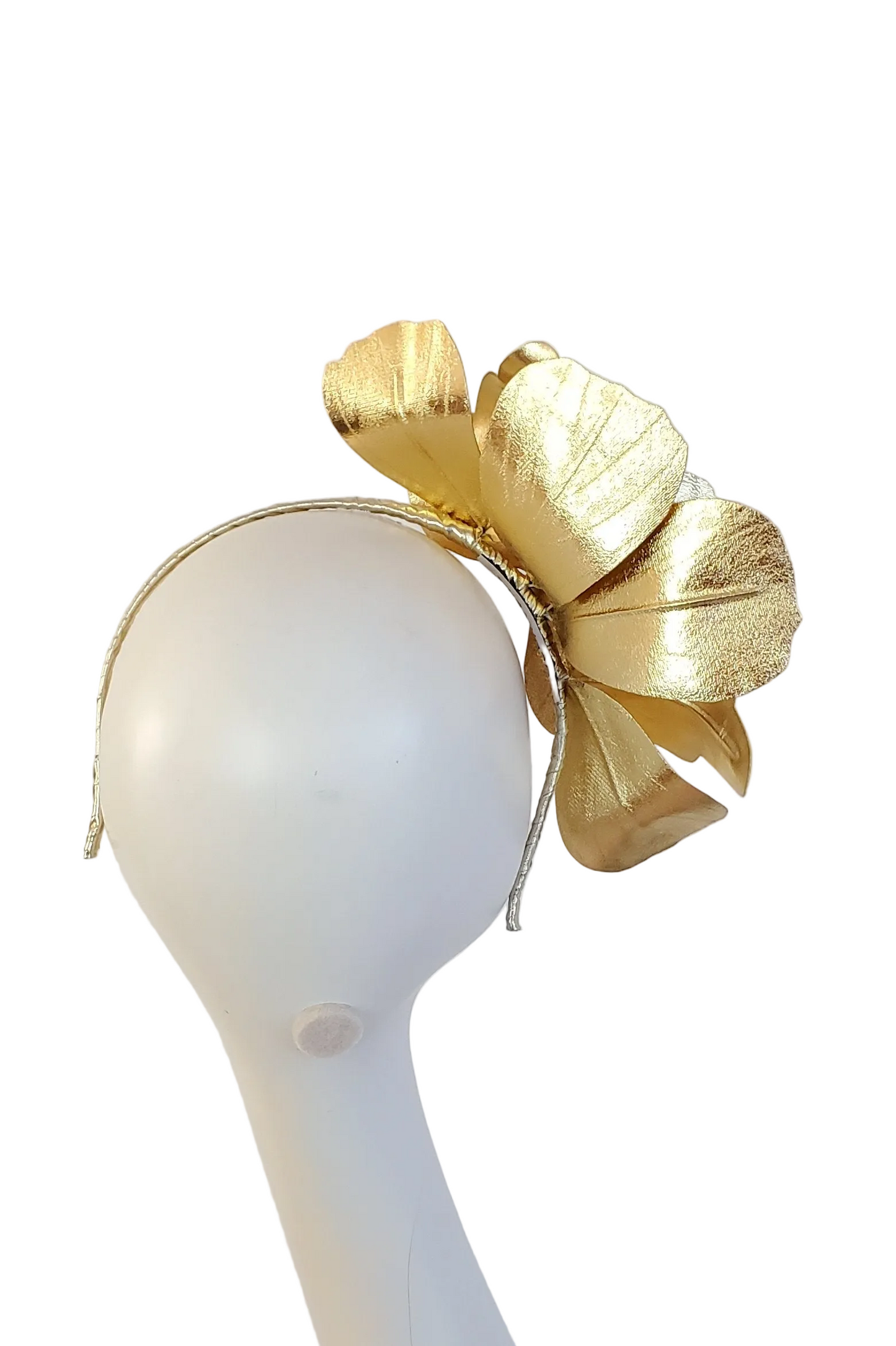 A gold metallic fascinator headpiece displayed on a white mannequin head against a white background.