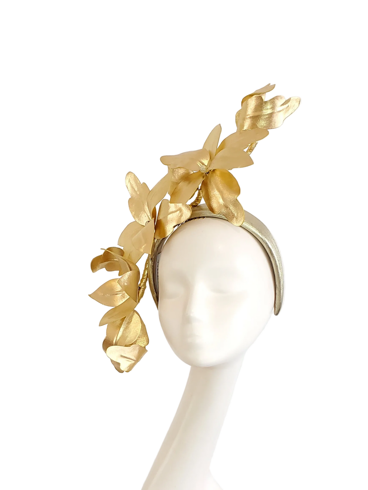 A gold metallic leaf fascinator headpiece displayed on a white mannequin head against a solid white background.