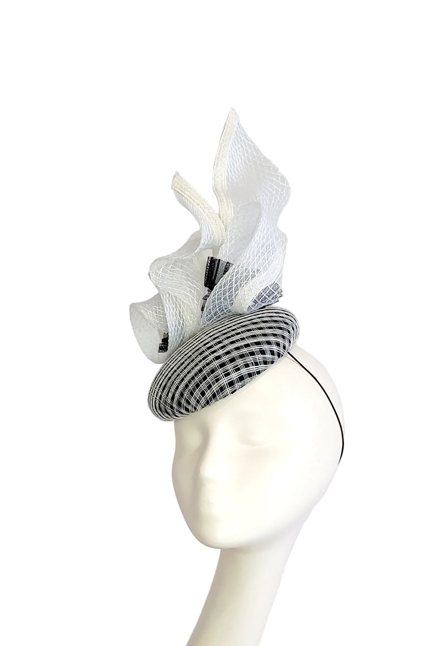 A black and white checkered fascinator has, displayed on a white mannequin head against a white background.