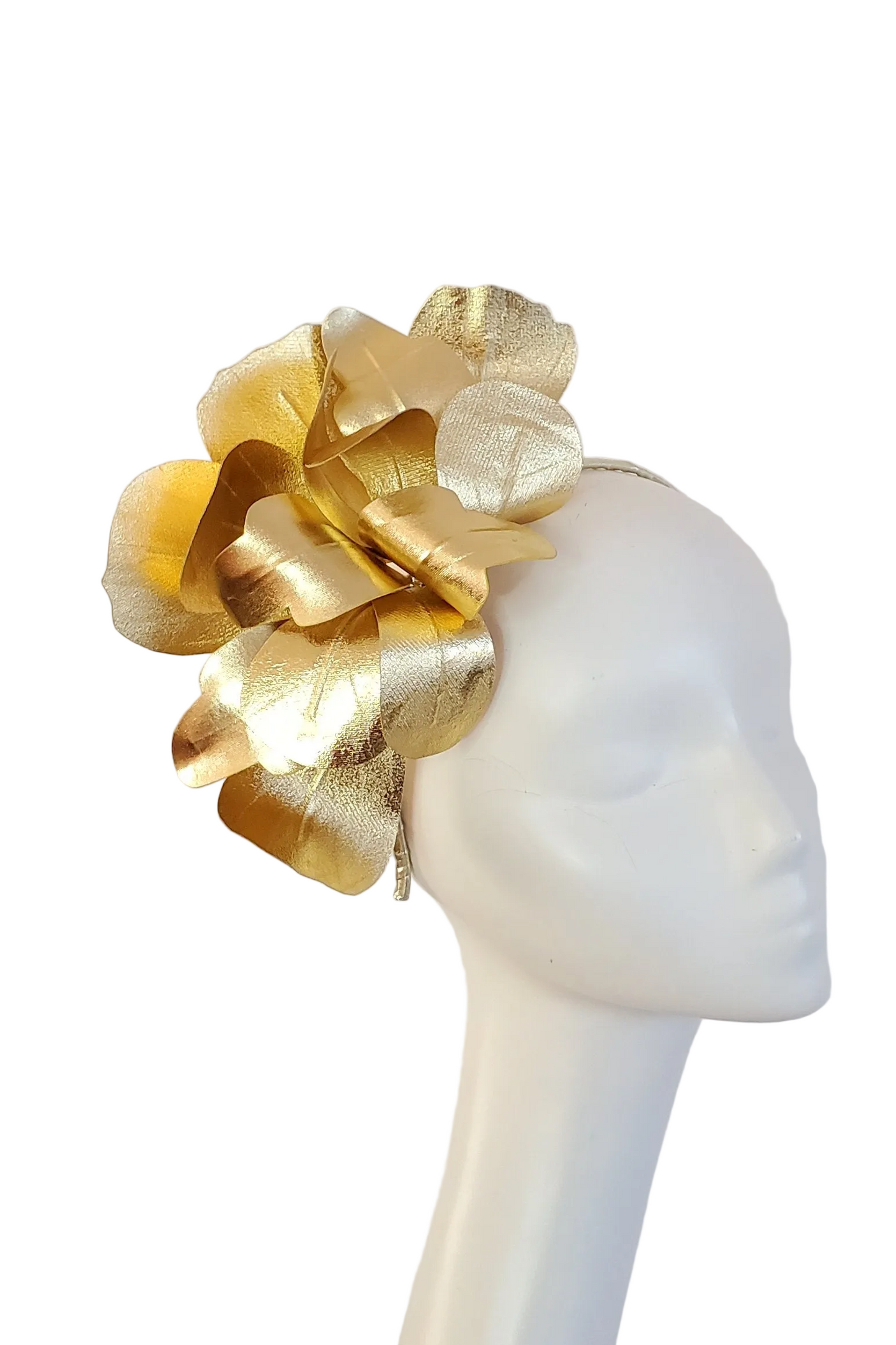 A large metallic gold fascinator headpiece with layered petal-like leaves, displayed on a white mannequin head against a plain light background.