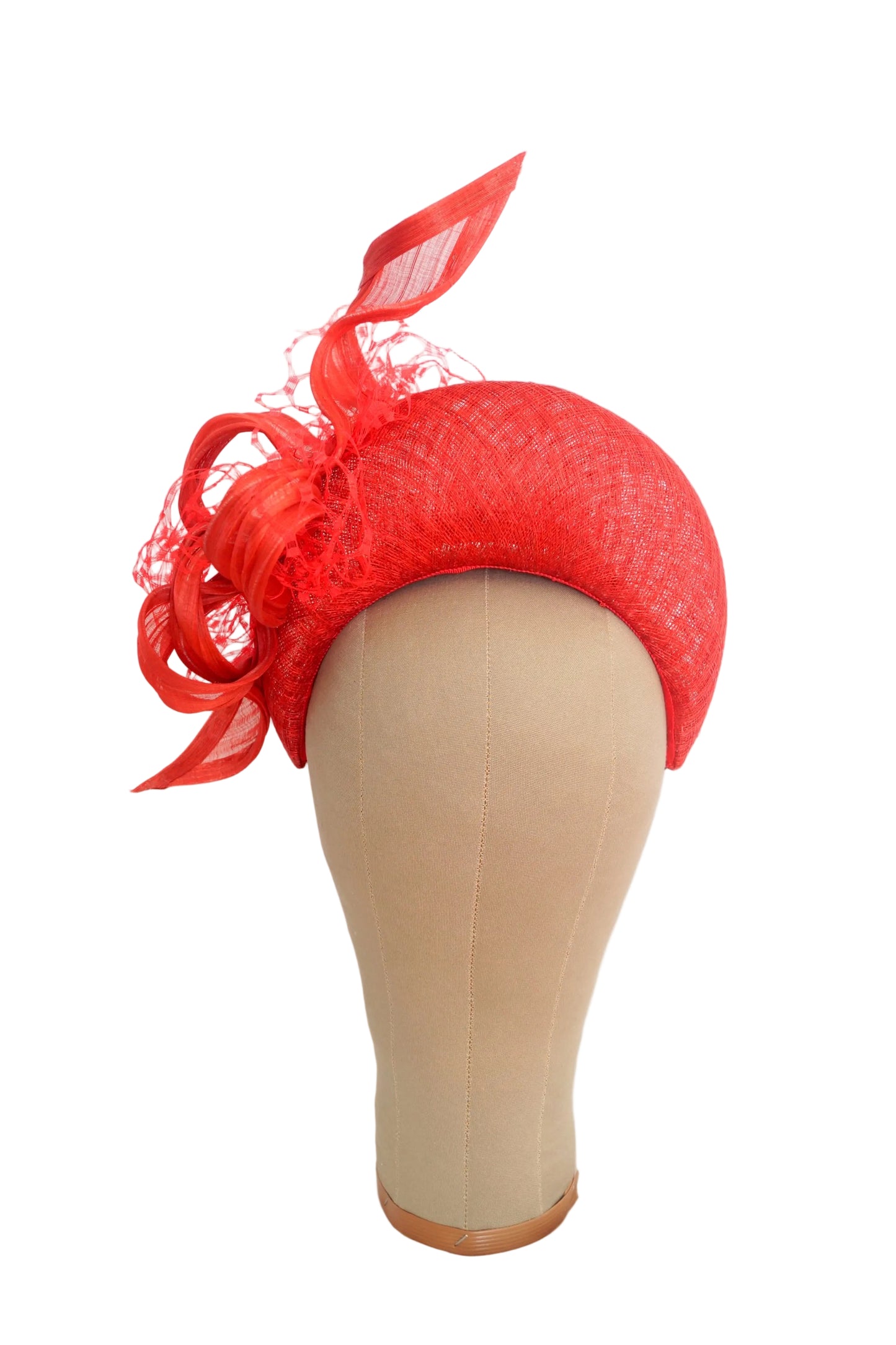 A bright red fascinator hat with matching red mesh and ribbon accents, displayed on a beige mannequin head against a white background.