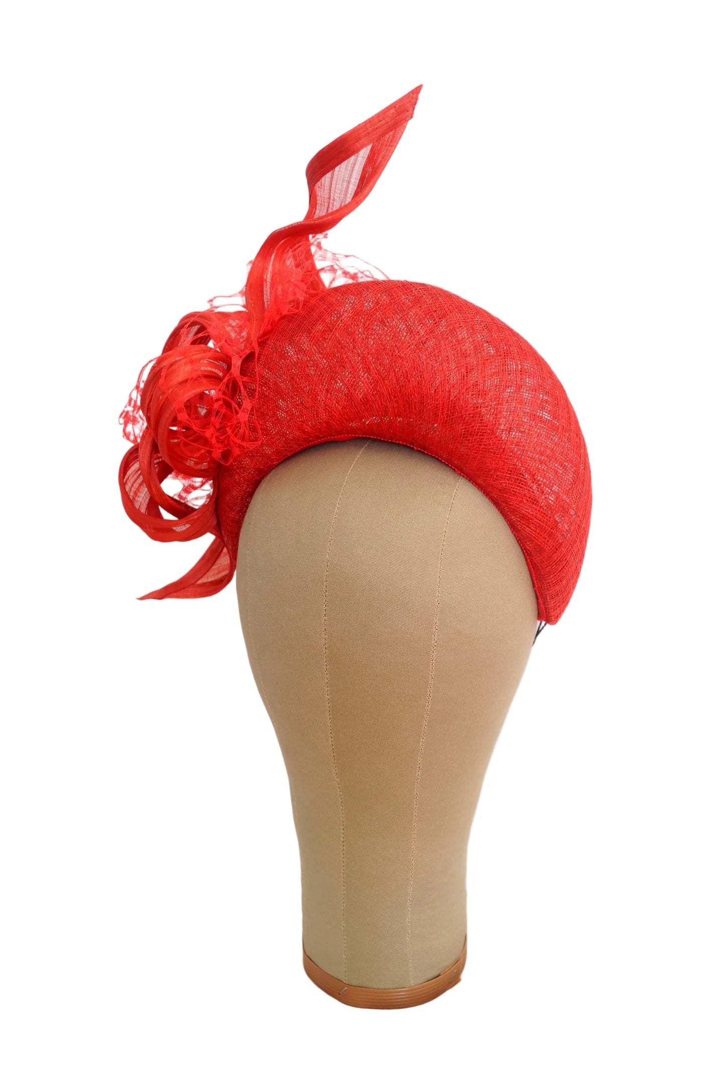 A bright red fascinator hat with matching red mesh ribbon, displayed on a beige mannequin head against a white background.