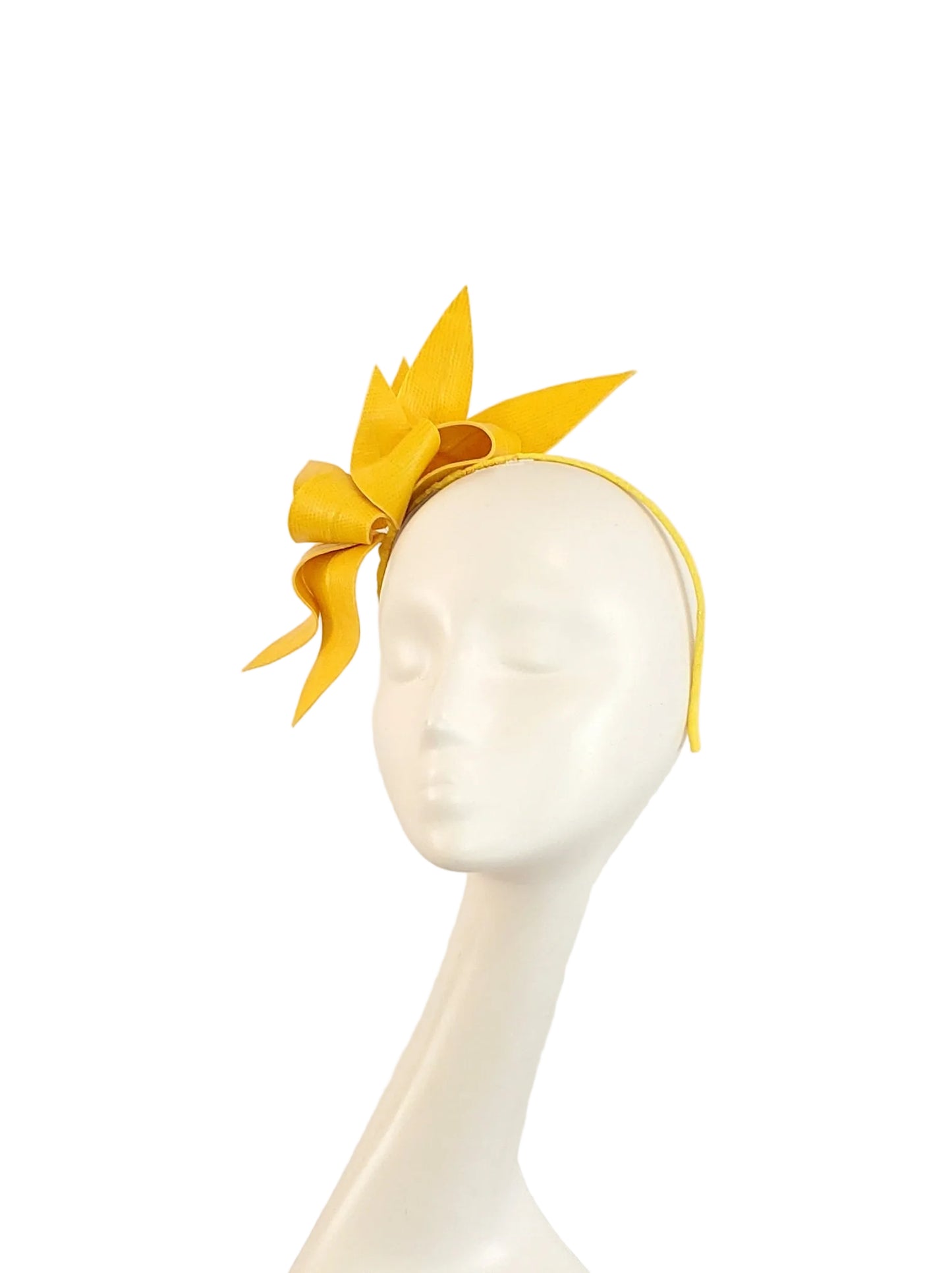 A bright yellow fascinator headpiece, displayed on a white mannequin head against a plain light background.